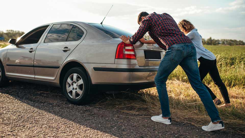 Ein Mann und eine Frau schieben ein Auto, weil das Auto nicht startet